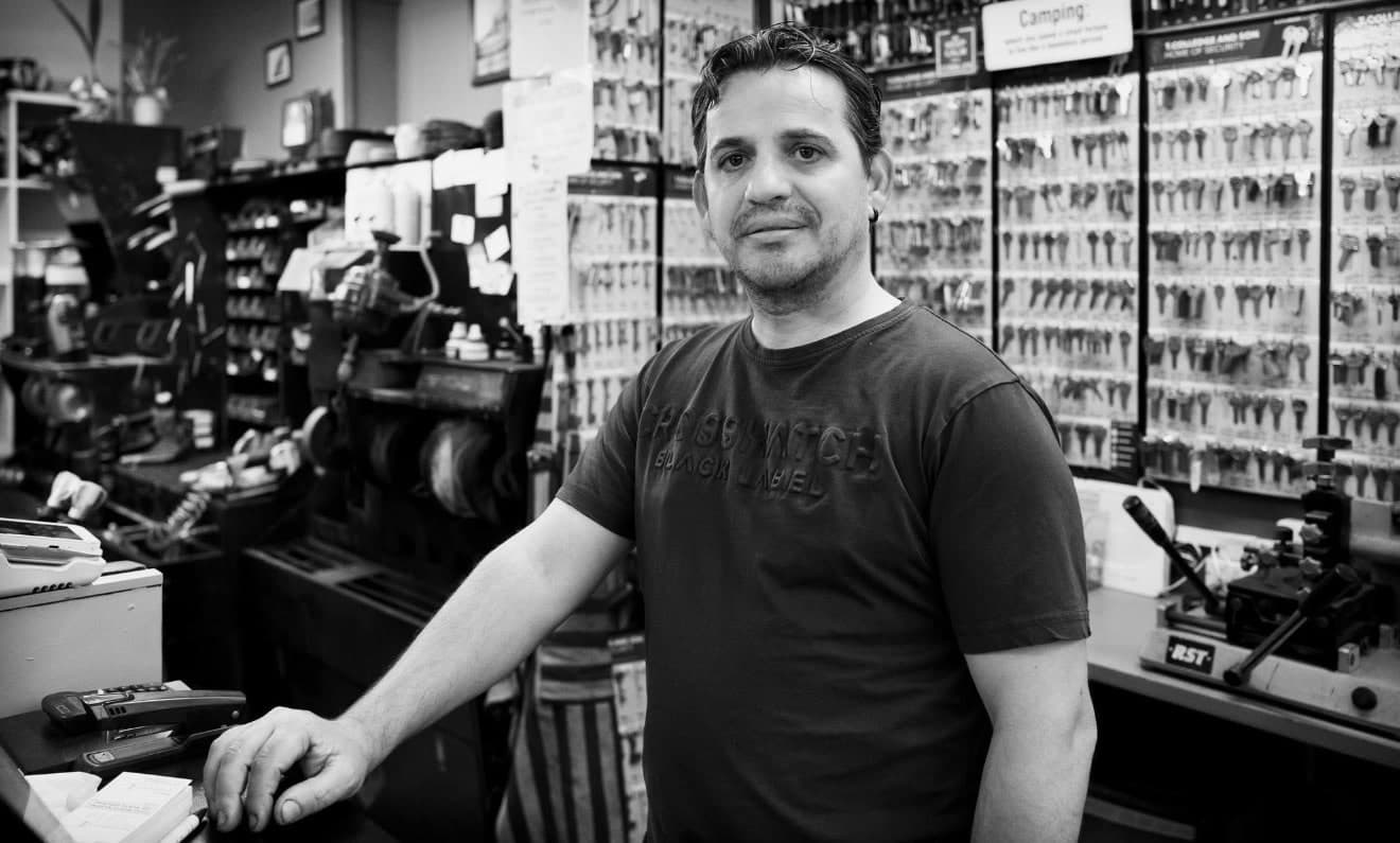 The cobbler behind the counter at Cobblers Guernsey, surrounded by key blanks and shoe repair machinery